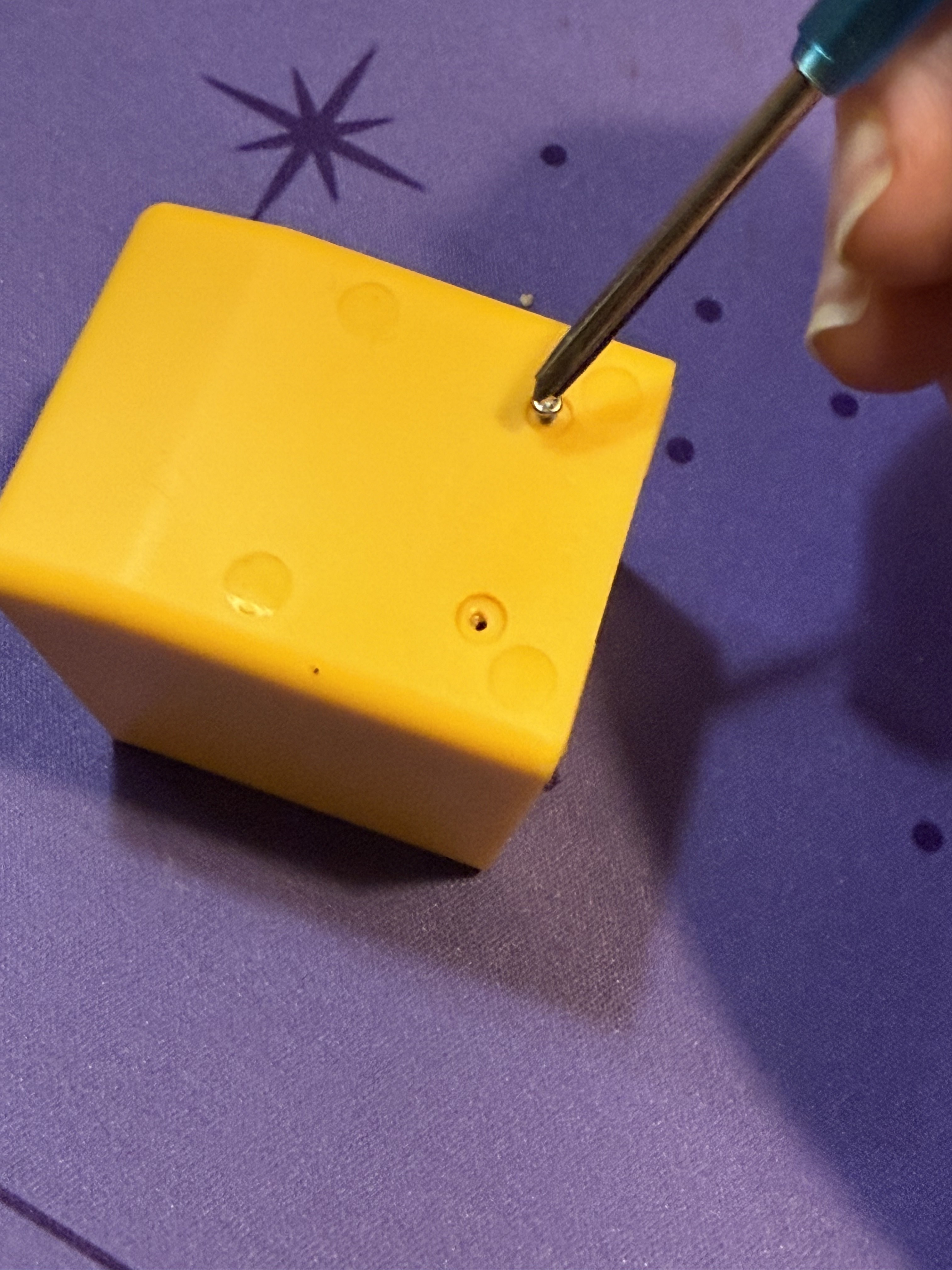 Unscrewing the bottom of the yellow case with a small screwdriver, two screw holes visible